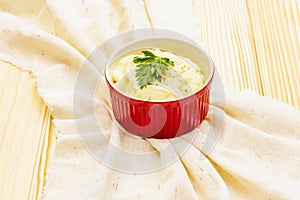 Warm mashed potatoes in a ceramic bowl with fresh parsley. On a vintage linen napkin on a stone background, copy space, close up