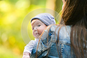 Warm mother`s hands. Happy mother walks with her baby in her arms. Mom talks to a happy child, the child sits in her mother s arm