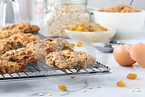 Warm oatmeal raisin cookies cooling on a metal cooling rack with recipe ingredients to the side.