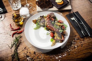 Warm octopus salad with stir fried vegetables and aji sauce on white plate. Delicious healthy mediterranean traditional