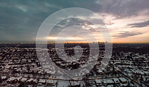 Warm Orange Sunrise Peeking Between Cool Clouds and Landscape Behind Chicago Skyline Silhouette, Drone View