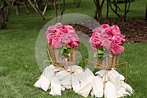 Warm pink blankets rolled up in the form of roses in a large basket for guests at an outdoor wedding party. Individual dance white