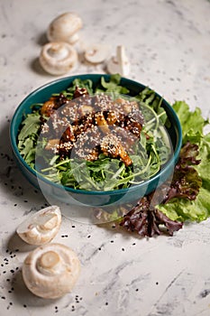 warm salad with mushrooms and arugula on a gray background