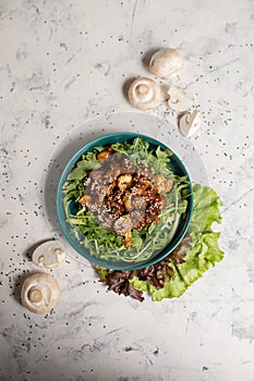 warm salad with mushrooms and arugula top view on a gray background