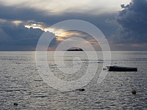 Warm sea sunset with cargo ship at the horizon . Giants cumulonimbus clouds are in the sky. Tuscany, Italy