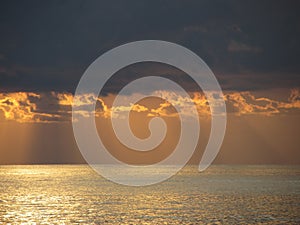 Warm sea sunset with giants cumulonimbus clouds in the sky and sun rays through . Tuscany, Italy