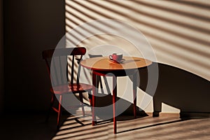 Warm sunlight casts shadows over a cozy table setting with a red cup