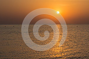 warm sunrise with reflections in the sea with waves and buoys