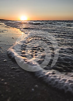 Warm sunset on the evening coast of the Black Sea with foamy sea surf