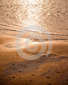 Warm sunset on textured sand beach