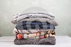 warm sweaters stacked on wooden table