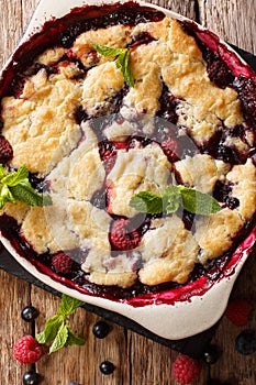 Warm sweet cobbler of raspberries and blueberries close-up in a