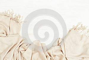 Warm textile scarf lies on white wooden surface. Light fashion woman palantine on wood. Autumnal background