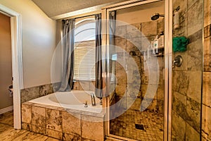 Warm toned bathroom with round bathtub tiles shower stall and arched window