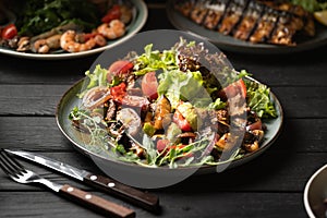Warm veal salad with lettuce served on a dark wooden table