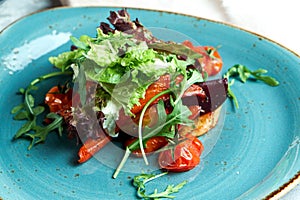 Warm vegetable salad with arugula, pepper, beetroot and tomatoes. Beautiful serving dishes. Light gray background