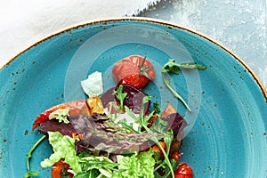 Warm vegetable salad with arugula, pepper, beetroot and tomatoes. Beautiful serving dishes. Light gray background