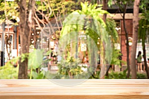 Warm wood table top Bar with blur on green palm leaves or tree in tropical forest with bokeh light
