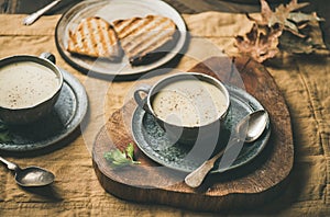 Warming celery cream soup and grilled bread over linen tablecloth