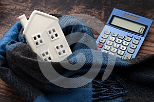 Warming efficiency of a residence and calculate heating costs concept with digital calculator, small house wrapped in warm wool