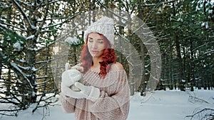 Warming fire in winter forest, pretty girl with red hair holding a burning candle in hands, flame candles, young woman