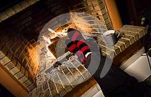 Warming her feet in a fireplace