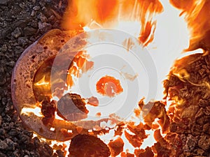 Warming iron in fire to create horseshoe on abvil