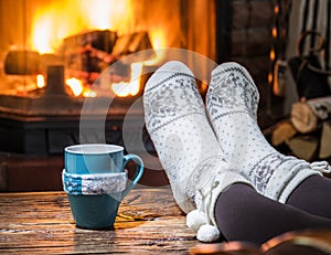 Warming and relaxing near fireplace with a cup of hot drink.