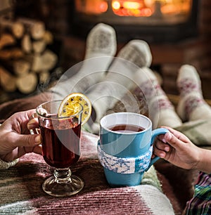 Warming and relaxing near fireplace with a cup of hot drink.