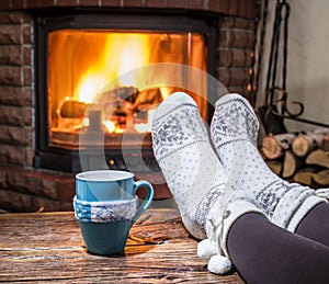 Warming and relaxing near fireplace with a cup of hot drink.