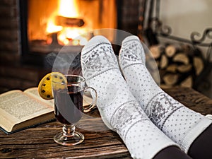 Warming and relaxing near fireplace with a cup of hot wine and a book