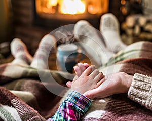 Warming and relaxing near fireplace. Mother and daughter holding