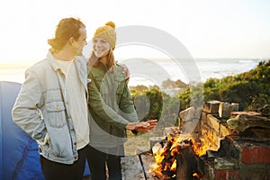 Warming up by the fire. an affectionate young couple getting warm by the fire.