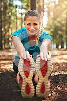 Warming up these muscles for a long run. a sporty young woman doing stretch exercise while out in nature.