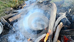 Warming up water in a metal saucepan on bonfire