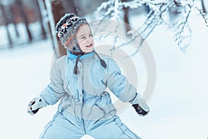 Warmly dressed boy playing in winter forest