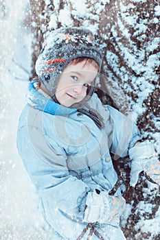 Warmly dressed boy playing in winter forest