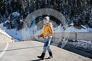 Warmly dressed little girl on a narrow mountain car brige at winter