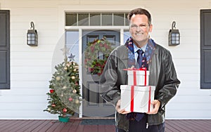 Warmly Dressed Man Holding Gifts Standing on Christmas Decorated Front Porch