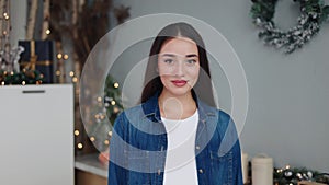 Warmly smiling brunette posed in a festive kitchen with shimmering garlands.