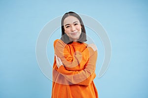 Warmth and tenderness. Cute korean girl hugs herself, embrace equite, femenism and international womens day concept photo
