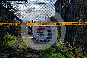 Warning, asbestos - a wire gate has a sign and tape warning of asbestos dust