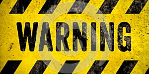 WARNING danger sign word text as stencil with yellow and black stripes painted over concrete wall cement texture background