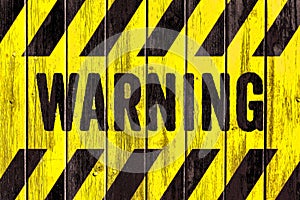 WARNING danger sign word text as stencil with yellow and black stripes painted on wood wall plank texture wide background