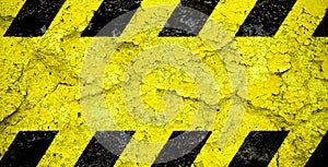 Warning danger sign yellow and black stripes pattern with yellow area over concrete cement wall facade peeling cracked paint