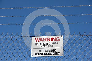 Warning Keep Out Sign On Chain Link Barbed Wire Fence