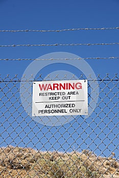 Warning Keep Out Sign On Chain Link Barbed Wire Fence In The Desert