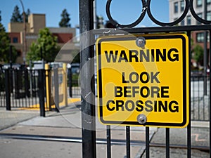 Warning look before crossing yellow warning sign at train station