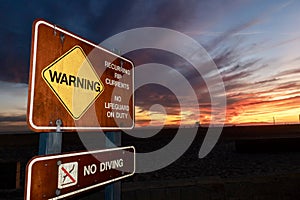 Warning rip currents sign with dramatic sunset