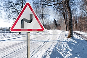 Warning road sign indicating a double bend in wintry conditions